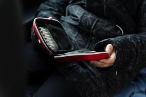 A person is holding in their hand a bright red case that contains various pills neatly organized inside it, which they might need for health purposes or a potential medical situation photo