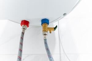 This is a closeup image of a water heater that features two hoses securely attached to it, showcasing the intricate details and components necessary for its operation and functionality photo