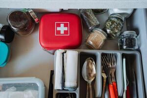 This is an organized kitchen drawer that features both a first aid kit and a collection of spice jars, enhancing accessibility and promoting safety for your family photo