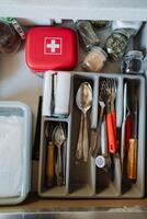 This drawer in the kitchen is meticulously organized to hold cutlery, spices, and a first aid kit, ensuring efficiency and neatness for all your cooking and dining needs photo