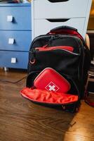 This trendy black and red backpack boasts a builtin first aid kit, making it perfect for emergency preparedness and outdoor activities such as hiking, camping, or travelling photo