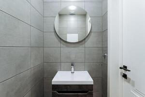 The bathroom features a beautifully designed sink along with a stylish mirror mounted on the wall, creating an aesthetically pleasing environment that enhances the overall space photo