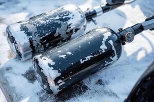 Two gas bottles are positioned and resting on a surface that is completely covered in snow, showcasing the cold winter environment surrounding them with its icy conditions photo