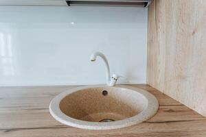 Discover a modern kitchen sink design with a sleek minimalist style and bright interior. Keywords cabinets, contemporary styles, stylish countertops, renovation ideas photo