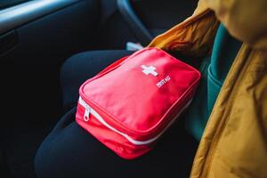 A person is comfortably sitting in a car with a first aid kit resting in their lap, ready for any potential accidents or emergencies that might occur during their journey photo