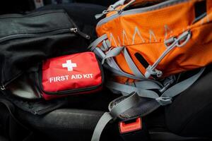 A stylish orange backpack sits next to a wellorganized first aid kit, essential for emergencies. This combo is a musthave for explorers and commuters, ensuring preparedness photo