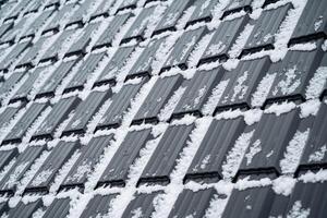 This closeup photo captures a beautiful snowcovered roof, highlighting the enchanting allure of winter against the grey and silver materials of the surrounding structure
