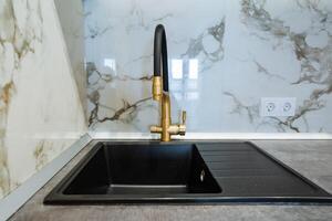 A modern kitchen features a sleek black sink paired with an elegant gold faucet, creating a striking contrast that enhances the overall visual appeal and makes it a focal point photo