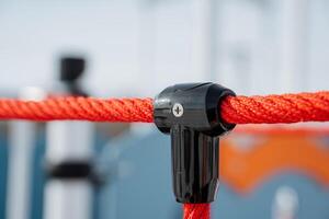 This image shows a closeup of a vibrant black and orange rope connector in a lively outdoor setting with playground equipment, capturing active recreation and joy photo