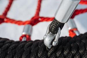 This image features a closeup of a black and red climbing rope with a metal clip and securely tied knot, perfect for outdoor activities and sports enthusiasts photo