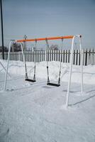 An Isolated Swing Set Nestled Within a Beautiful Winter Wonderland A Stunning and Peaceful Playground Scene, Covered Generously in a Soft Layer of Sparkling Snow and Stillness photo