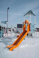 A vibrant and colorful playground slide, beautifully surrounded by a blanket of snow, creates an enchanting winter landscape for children to enjoy and explore safely photo