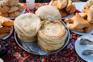 Indulge in a delightful variety of mouthwatering traditional flatbreads and savory pastries displayed beautifully on a vibrant and colorful table setting for all to enjoy photo
