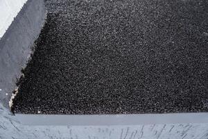 This image provides a closeup view of a black bituminous roof surface, showcasing its textured finish and appearance, ideal for construction and rooftop applications photo