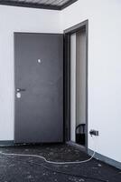 A minimalist gray door paired with an open frame is prominently featured in a spacious, empty environment, accompanied by a visible power cord adding a functional element photo
