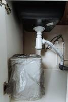 A trash can is presently placed under the sink located in the kitchen area, serving as a very convenient receptacle for all types of waste and disposal of garbage generated during cooking photo