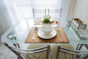 A beautifully designed glass dining table that features an arrangement of elegant plates and bowls neatly placed upon it, showcasing a stylish and modern dining experience in your home photo