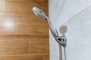 In a bathroom, there is a shower head that is securely hanging on a tiled wall, providing a necessary fixture for daily hygiene and cleanliness routines in such a personal space photo