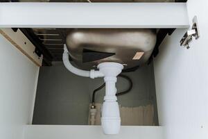 There is a kitchen sink that features a drain pipe situated beneath it, which can be found housed within the cabinetry below. This setup is essential for proper plumbing function photo