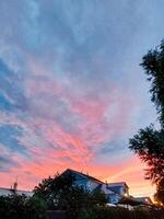 A picturesque sunset featuring a charming house prominently positioned in the foreground, while tall trees elegantly rise in the background, creating a beautiful natural scene at dusk photo