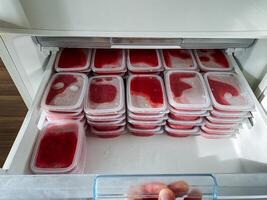 A very large freezer that is completely filled with a multitude of containers brimming with delicious strawberry ice cream, ready to be enjoyed at any time for a delightful dessert photo