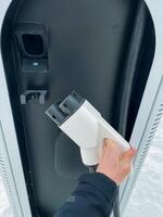A person is connecting their electric vehicle to a charging station, ensuring that it is powered up and ready for use, showcasing the advancements in technology and electric mobility photo