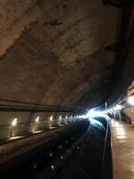 A dark and mysterious tunnel, which is dimly illuminated by a few flickering lights mounted on the walls, creates an eerie atmosphere that greatly enhances the overall sense of adventure photo