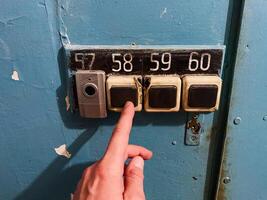 A persons finger is currently pointing directly at the specific number 57 that is displayed on a vibrant blue door, indicating an important or significant reference point photo