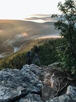 The breathtaking view of a vast mountain valley can be admired from the top of a rugged rocky cliff, showcasing the beauty of natures majesty and serene wilderness all around it photo
