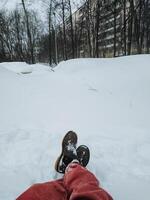 A person is currently lying comfortably in the soft, white snow with their feet raised high up into the air, taking in and thoroughly enjoying the cold and wintry weather surrounding them photo