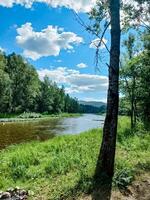 A picturesque river flows gently through lush green trees on a sunny day, creating a peaceful scene perfect for relaxation and appreciation of natures beauty and harmony photo