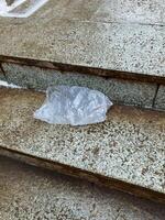 A plastic shopping bag is resting on a staircase made of concrete, marble, or granite, drawing attention to the distinctive architectural features of the building surrounding it photo