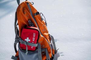 A backpack that contains a first aid kit is resting on the snowcovered ground, waiting to be used in case of any emergencies or injuries that may occur in the snowy surroundings photo