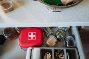 A meticulously organized kitchen drawer that combines a first aid kit alongside glass jars filled with essential cooking ingredients for efficient functionality and safety photo