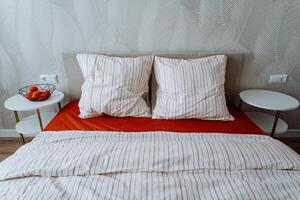 In a cozy bedroom, there is a comfortable bed adorned with vibrant red sheets and soft white pillows that provide a beautiful contrast and enhance the overall aesthetic of the room photo