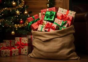 A burlap sack bursting with colorful Christmas presents sits by the glowing tree, ready for gifting. photo