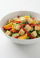 A colorful tofu salad with fresh oranges, crisp cucumbers, and red bell peppers. photo