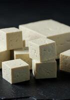 Tofu cubes and blocks stacked on slate, ready to be used in a healthy, vegan meal. photo