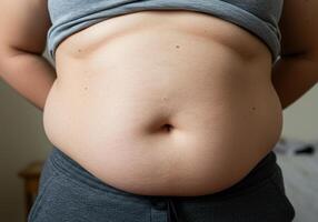 A person's midsection is slightly overweight with gray clothes on in a close up. photo