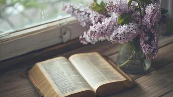 Open bible on the wood table and a bouquet of flowers in a vase next to, christian concept, lilac photo