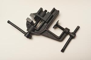 A little metal vise in his hand. The clamping tool. Locksmith instruments. photo
