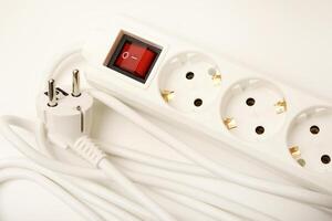 A white multi-plug extension cord with three receptacles on a snow-white surface. photo