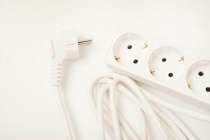 A white three-socket power cable with outlets on a neutral white base. photo