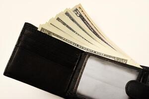 A dark wallet with a stack of banknotes displayed on a white canvas. photo
