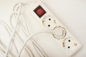 A three-port electrical strip with an ivory-colored wire displayed on a white base. photo