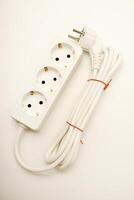 A three-socket extension lead featuring a white cord against a pale background. photo