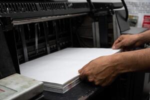 Operator Loading Paper into Industrial Printer Printing Process. High quality photo