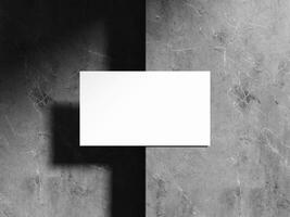 A minimalist business card mockup on a textured dark stone background with sharp light shadows, perfect for showcasing elegant brand identity designs. photo