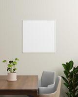 A white square photo frame on a neutral wall with a table, plant, and chairs, offering a bright, fresh backdrop for art or photography displays.