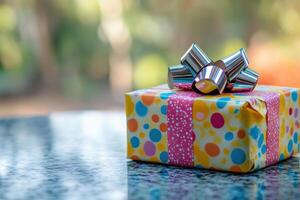 Joyful birthday gift wrapped with colorful paper and shiny bow on the table. photo